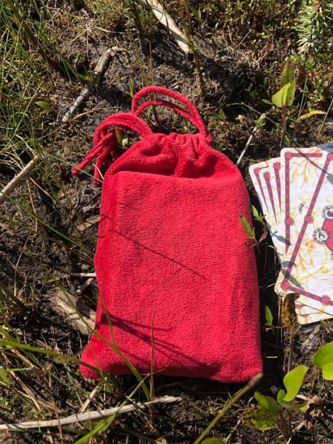 The red velvet-like bag created for the harrow cards, sitting on the ground.