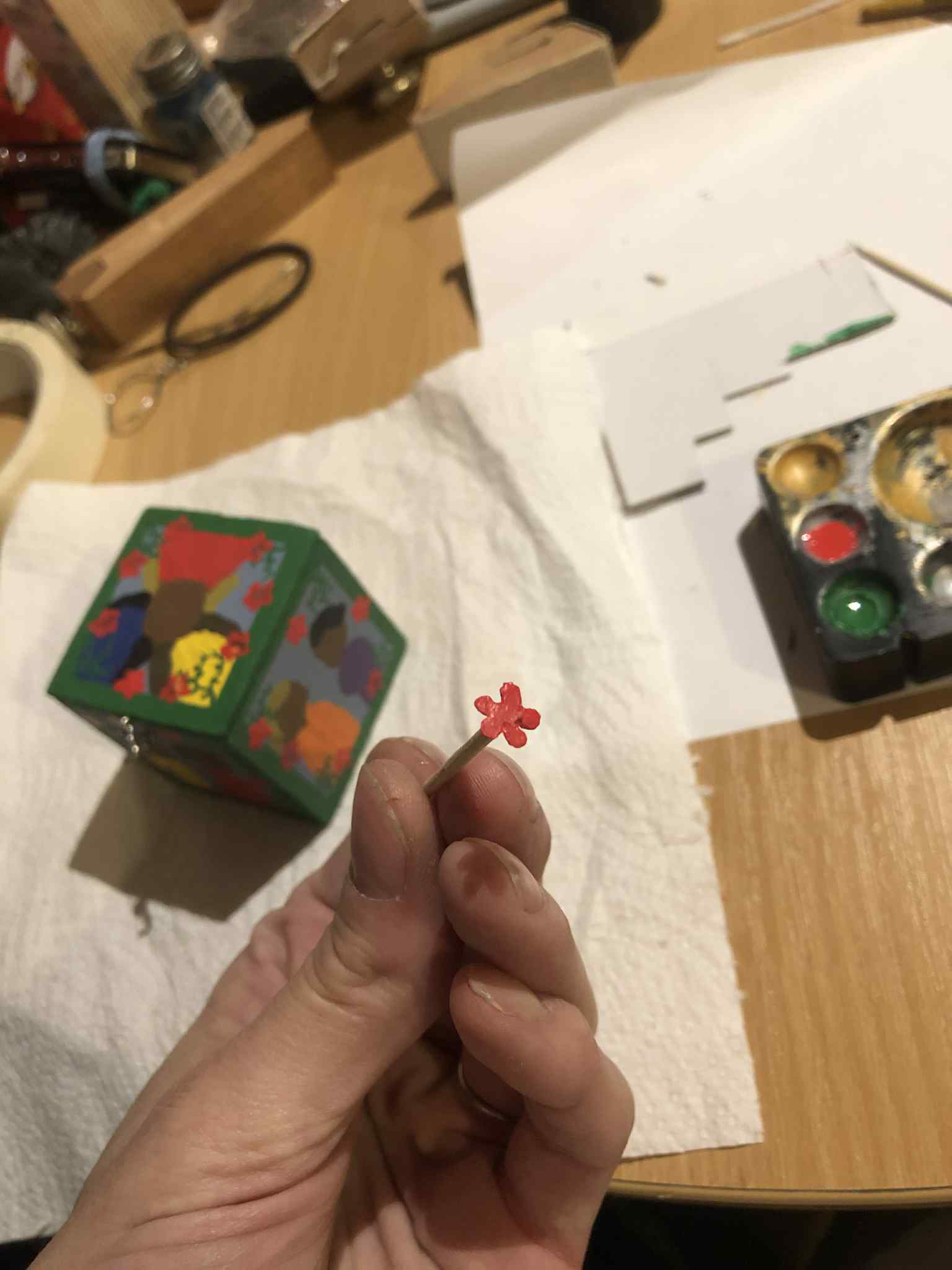 The box mostly painted in the background, with the borders, vinework, and initial red flowers now painted on. I'm holding up a toothpick with a little red stamp for the five petal flower that I was using to place all of the flowers on the box.