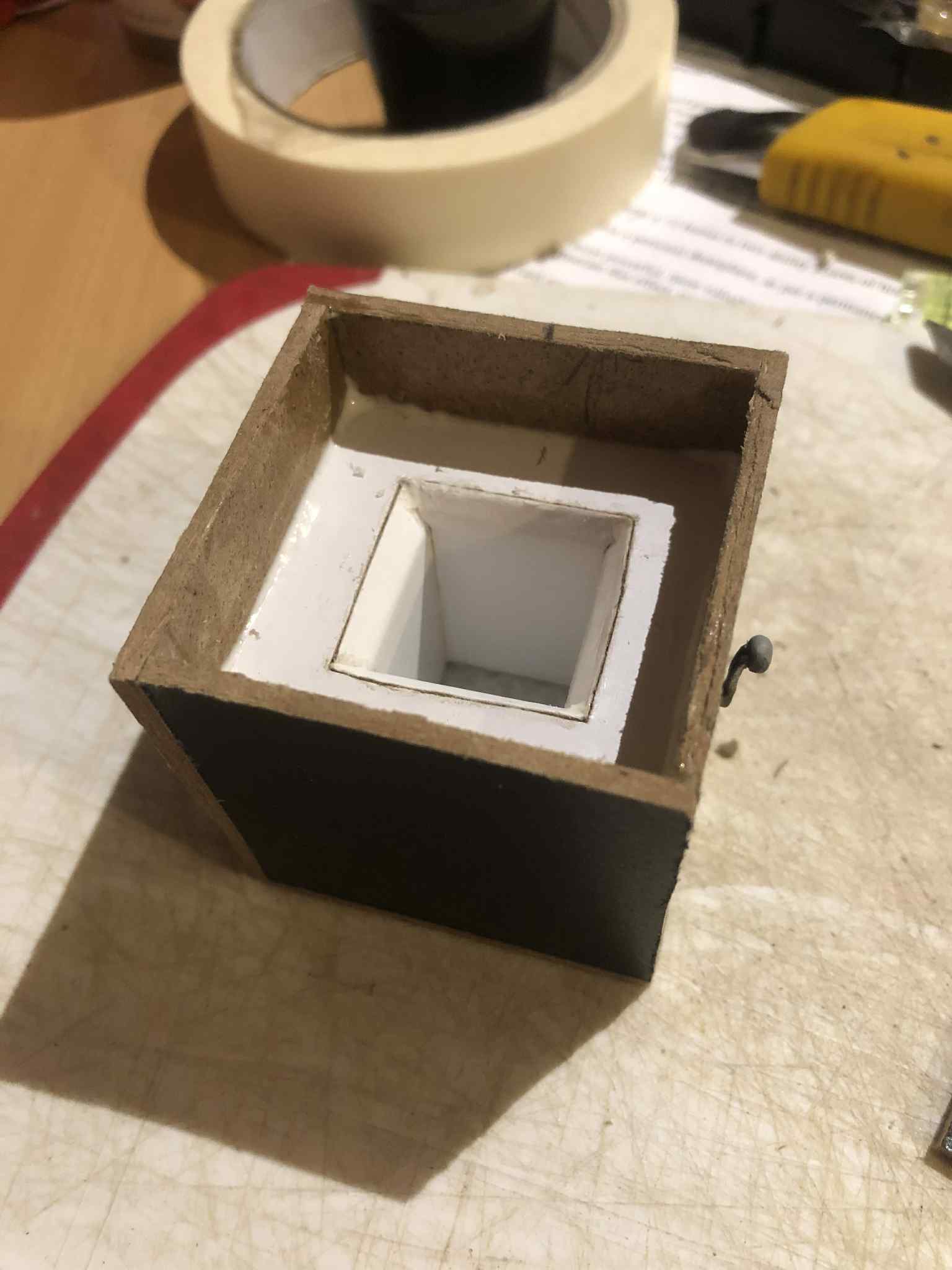 The bottom of the box fully constructed, with the inner structure having a lip that extends to the outer walls to seal the bell fully inside of the hollow interior.