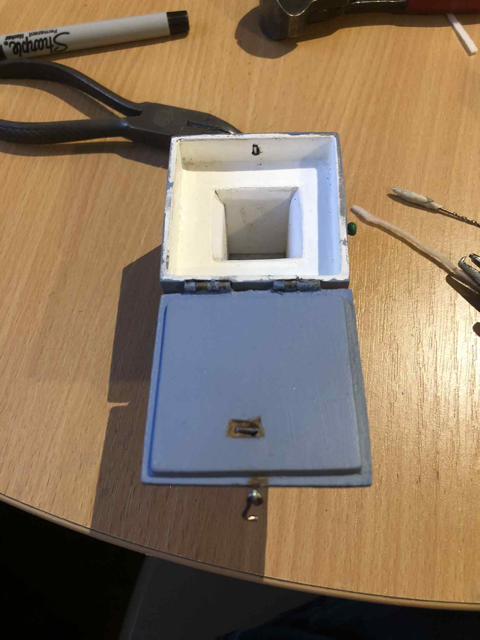 The lid now attached with hinges, and the clasps attached to the lid and front of the box, showing little cutouts partway through the box material for the wire to be bent over inside of, so that the inside of the box can be kept flush with no metalwork visible.