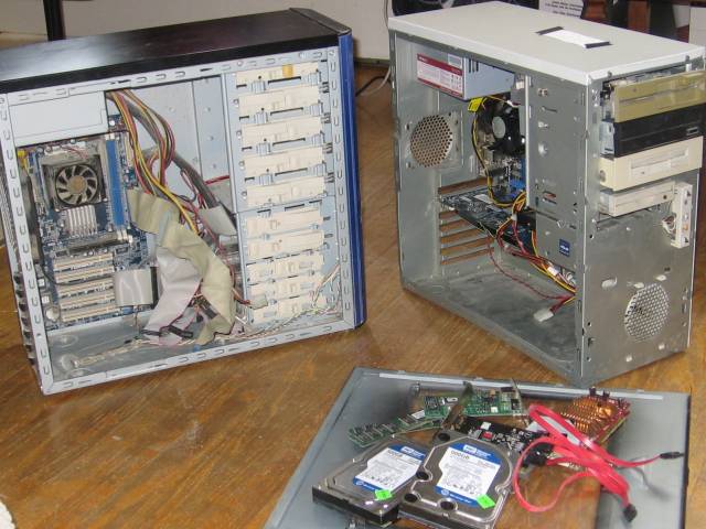 The two computers beside eachother and opened up. Several hard drives are sitting on one of the casing sides.