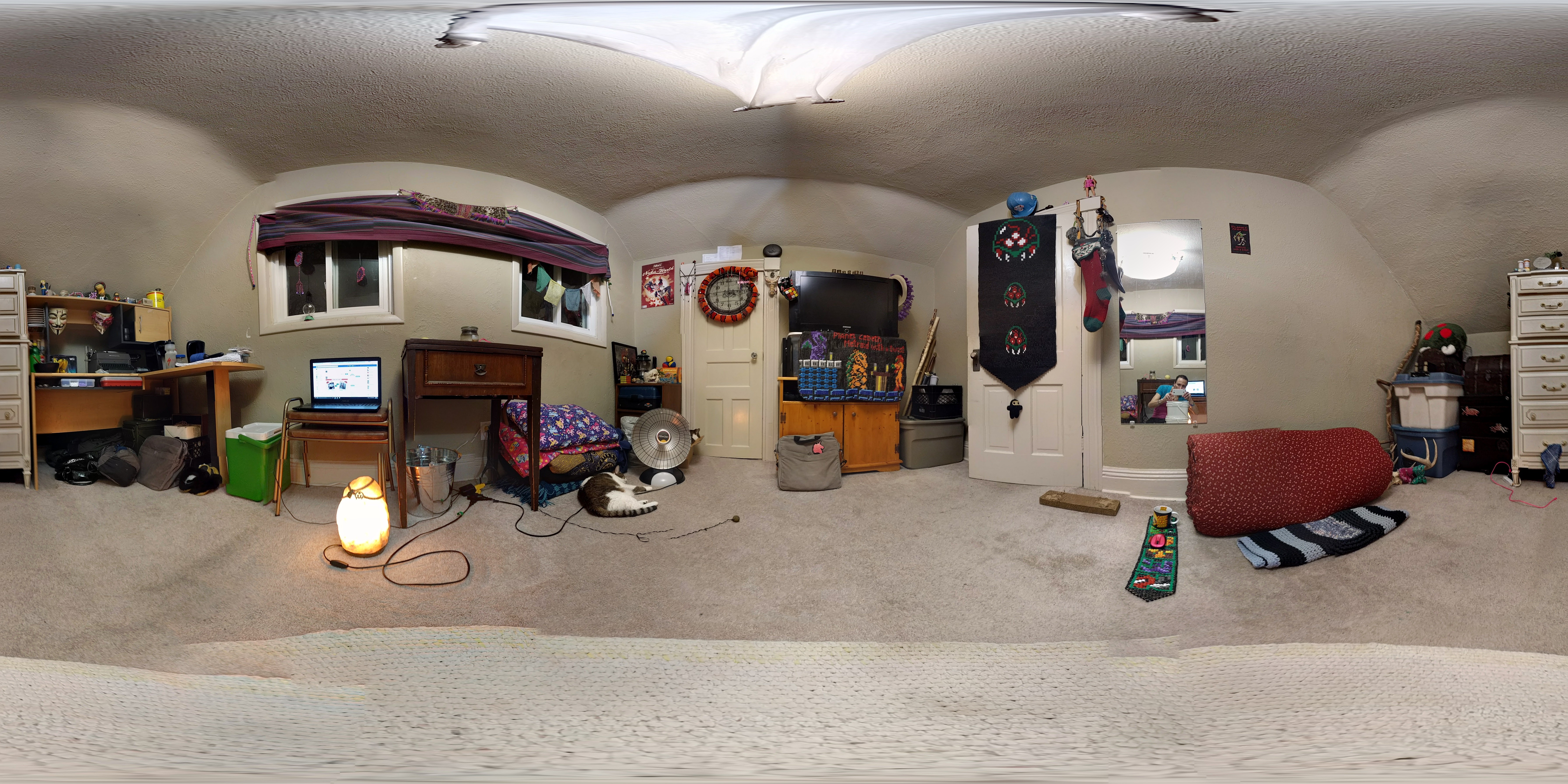 A small room with pale carpet, a desk with miscellaneous stuff on it, the beaded banners hanging in places, and also Kabutroids bedroll against a wall.