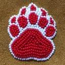 Red beaded bear paw with a white outline, on medium brown leather