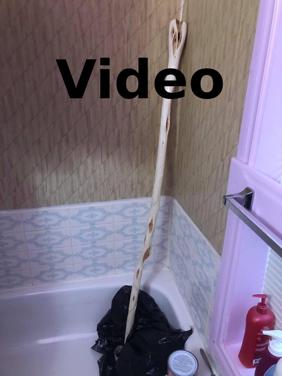 A photo of the staff up in the corner of the bathtub for varnishing, with text saying Video at the top.