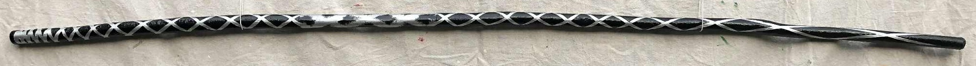 A painted black staff with silver diamondpattern linework, running from long, tall diamonds at the bottom to tightly, narrow diamonds at the top, as though bolts of electricity were coiling up at the head of the staff, and extending through the bottom.