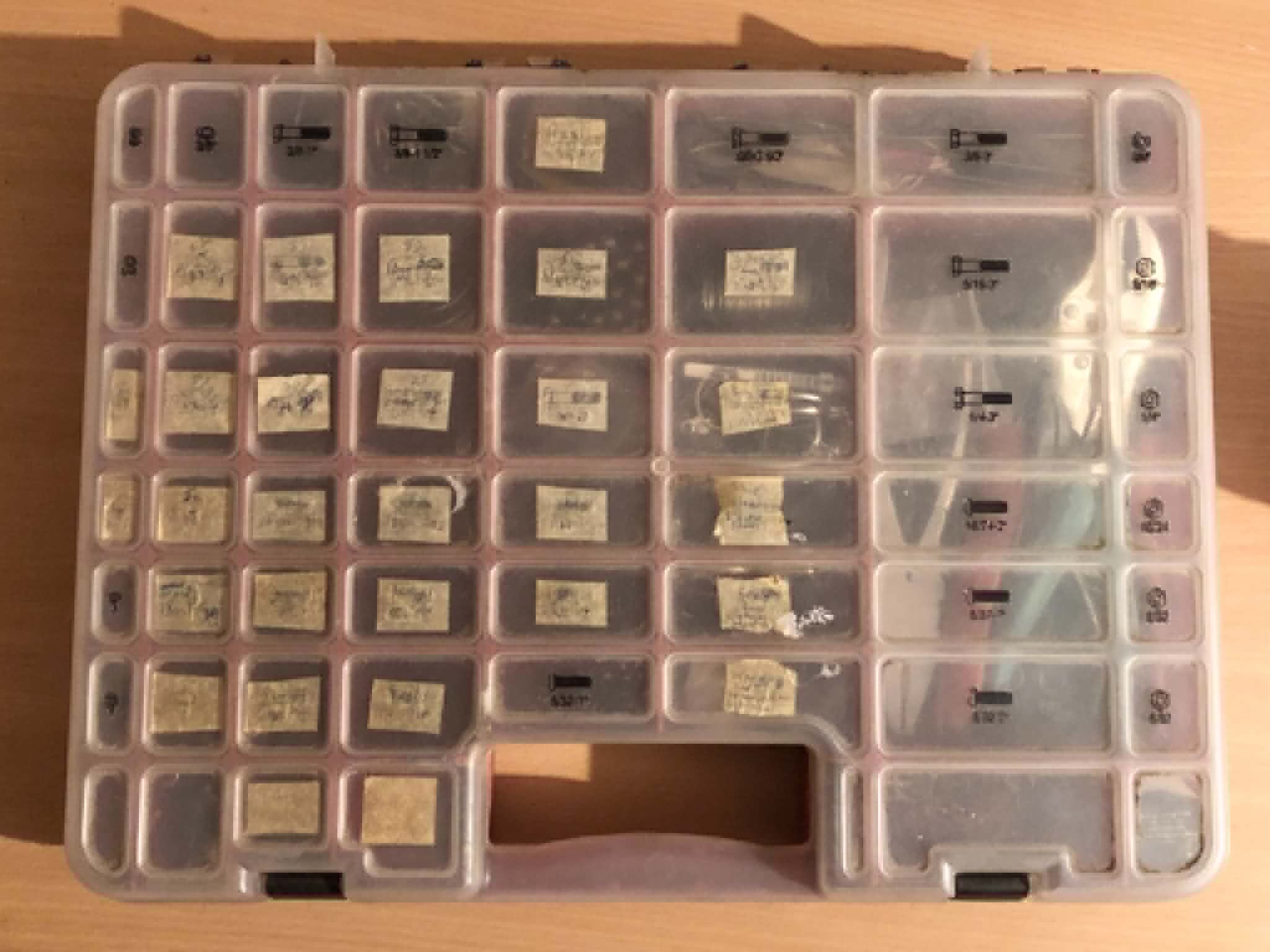 Our original chainmailling kit, a large multi slot organizer with 47 pockets, labelled with nearly unreadable pen on painters tape squares, and the rightmost pockets combined together to allow pliers to fit inside.