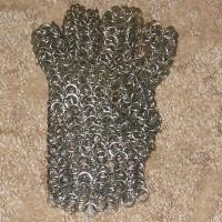 A brownish grey chainmaille glove on a brown rug
