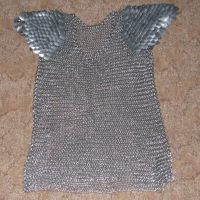A chainmaille shirt with scale shoulders on a brown rug