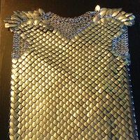 A scalemaille shirt with no sleeves laying on a black countertop