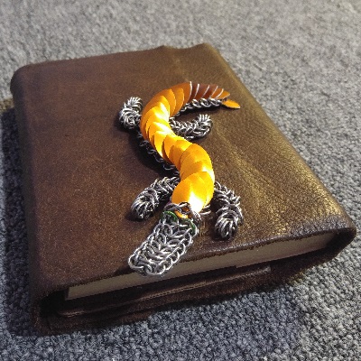 An orange gecko on a brown leather journal