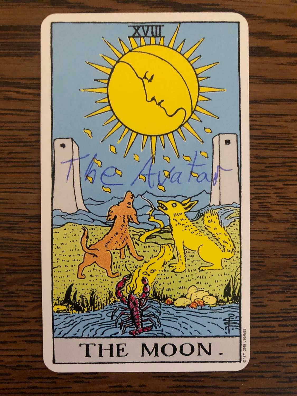 The moon card with the avatar written on it, laying on a wooden desk.