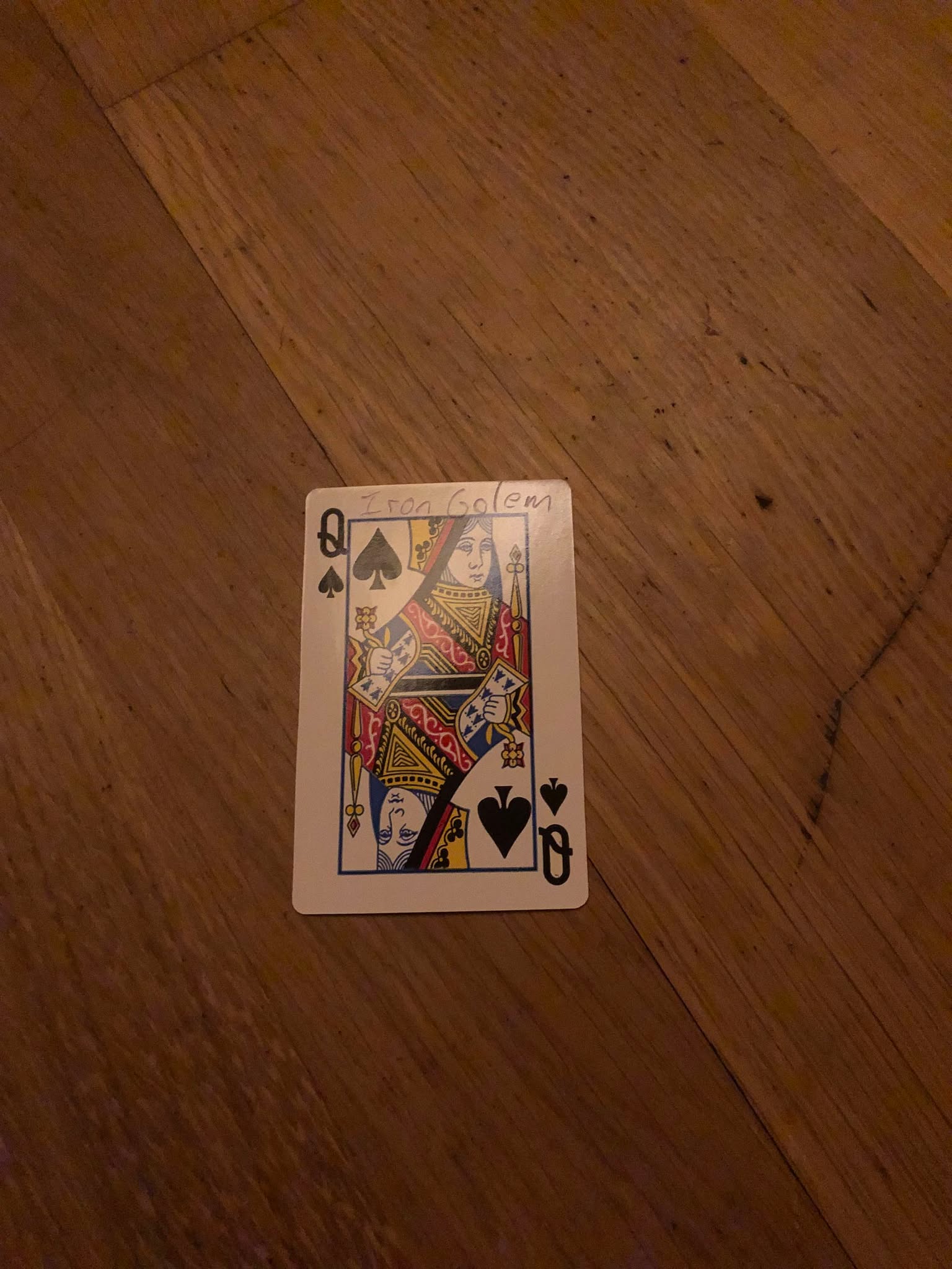 The queen of spades, thrown to the floor in front of the creature.