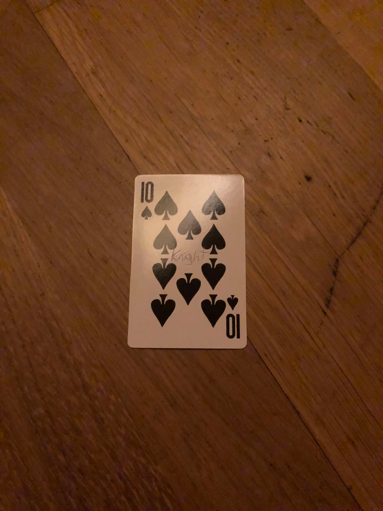 The ten of spades, thrown to the floor in front of the creature.