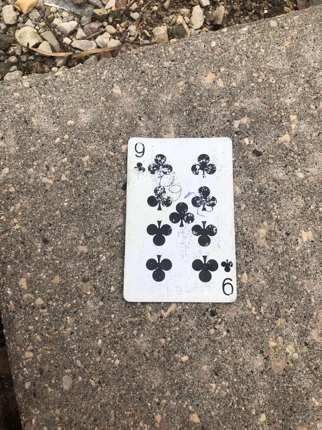 The nine of clubs, laying on the ground before the creature.