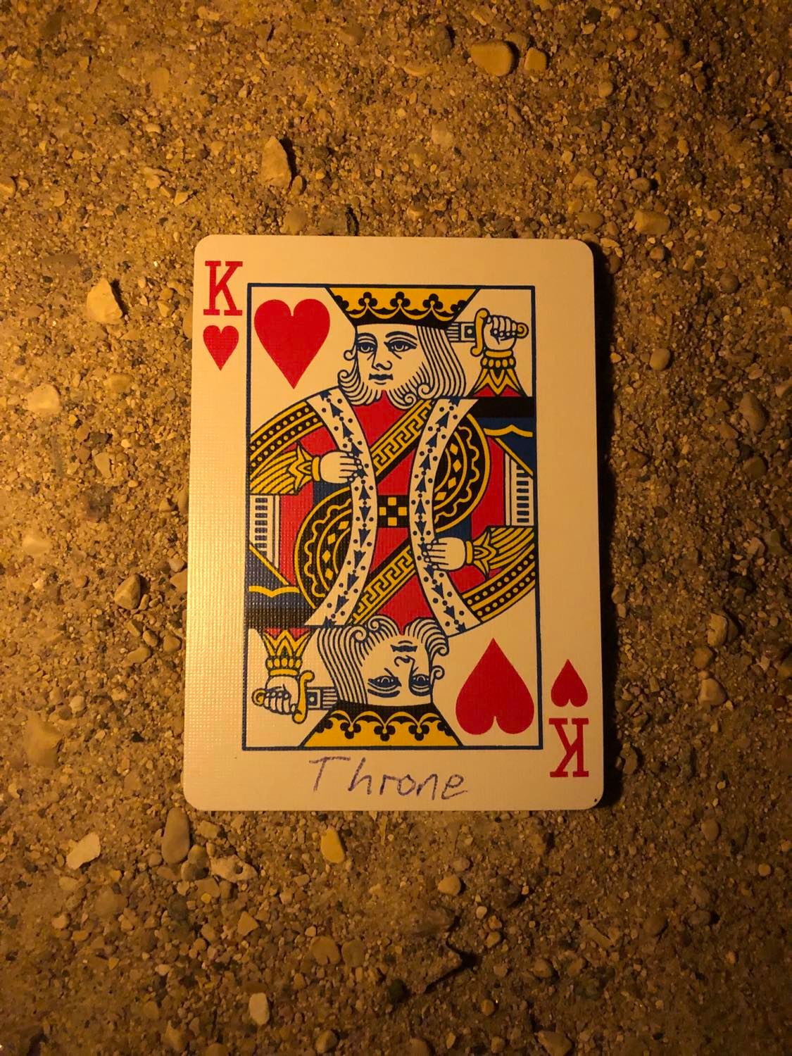 The king of hearts with Throne written on it, laying on the darkened soil.