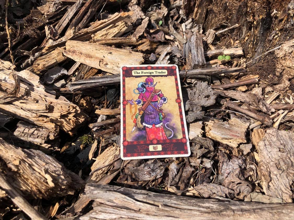 A blue celestial figure, the card laying on the forest debris.