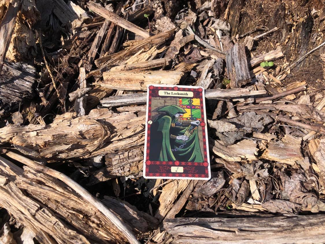 A thief picking a lock, the card laying on the forest debris.