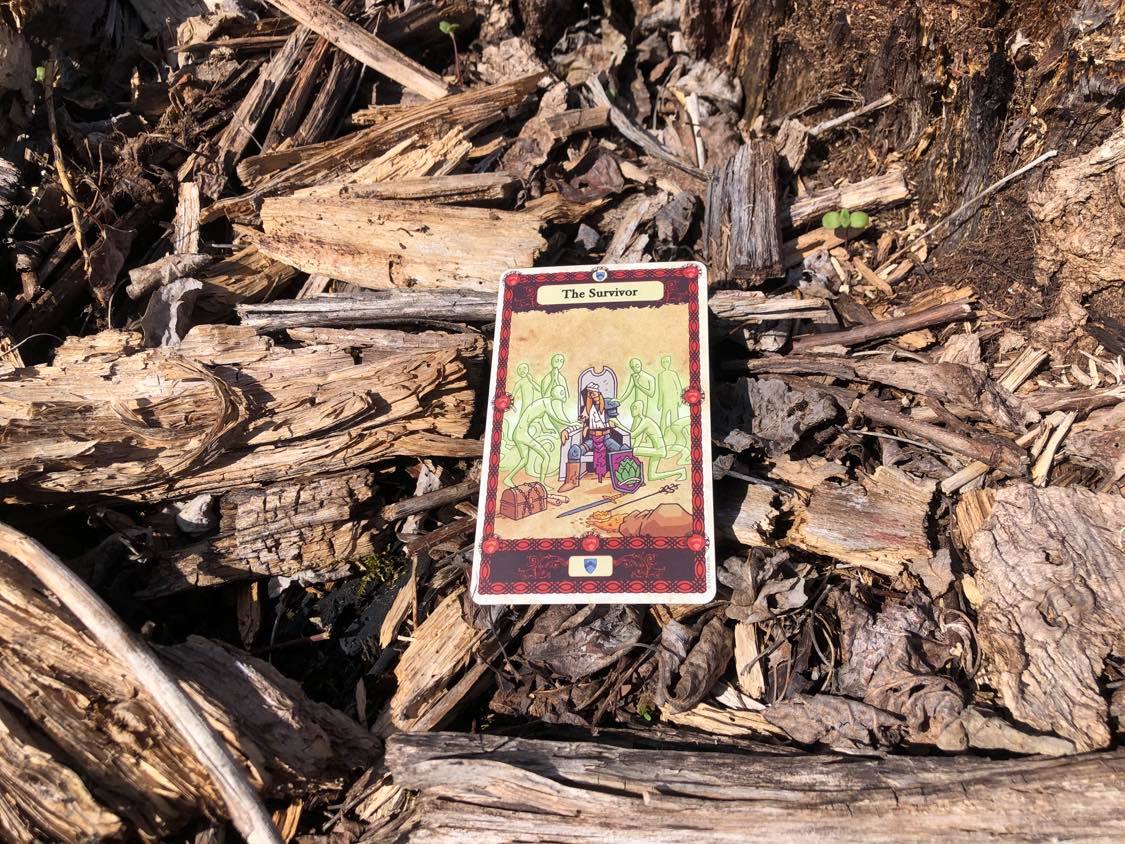 An injured soldier surrounded by caring spirits, the card laying on the forest debris.