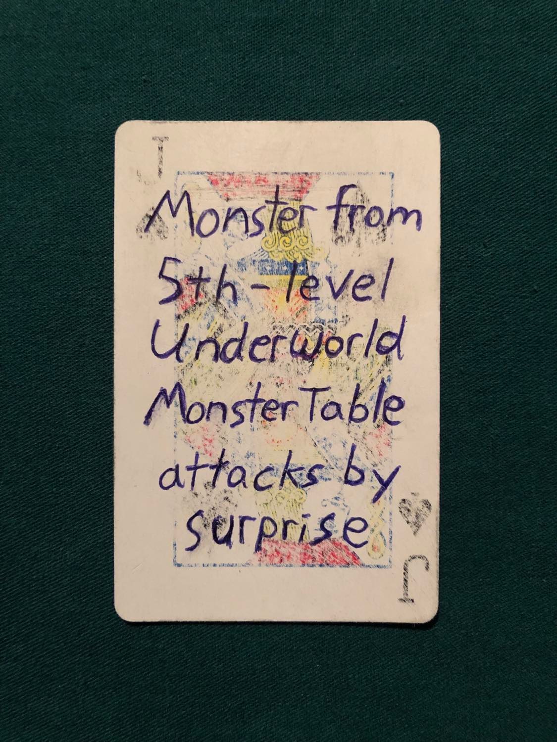 The jack of spades, laying on a green fabric.