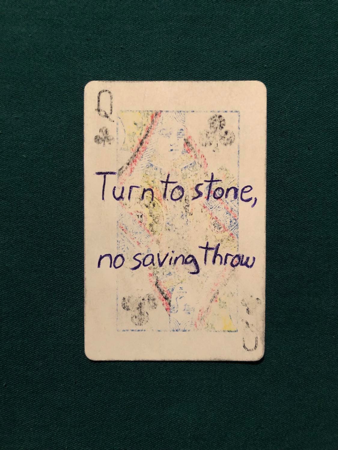 The queen of clubs, laying on a green fabric.