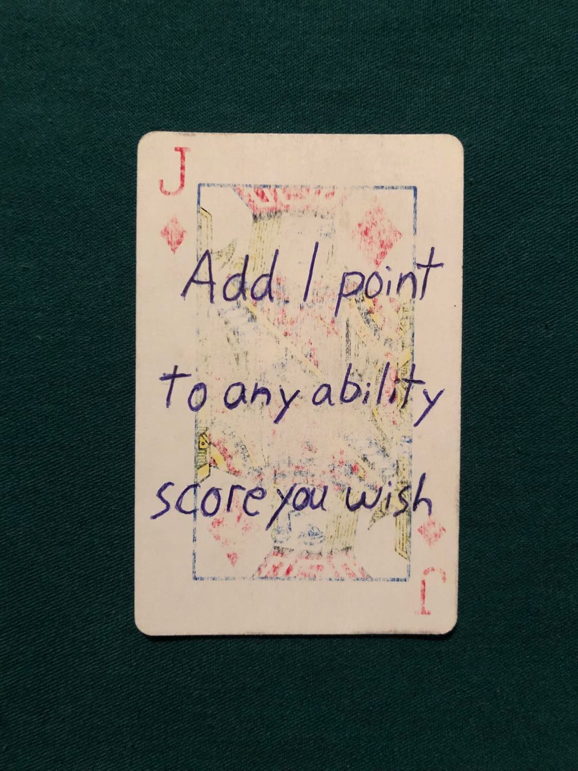 The jack of diamonds, laying on a green fabric.