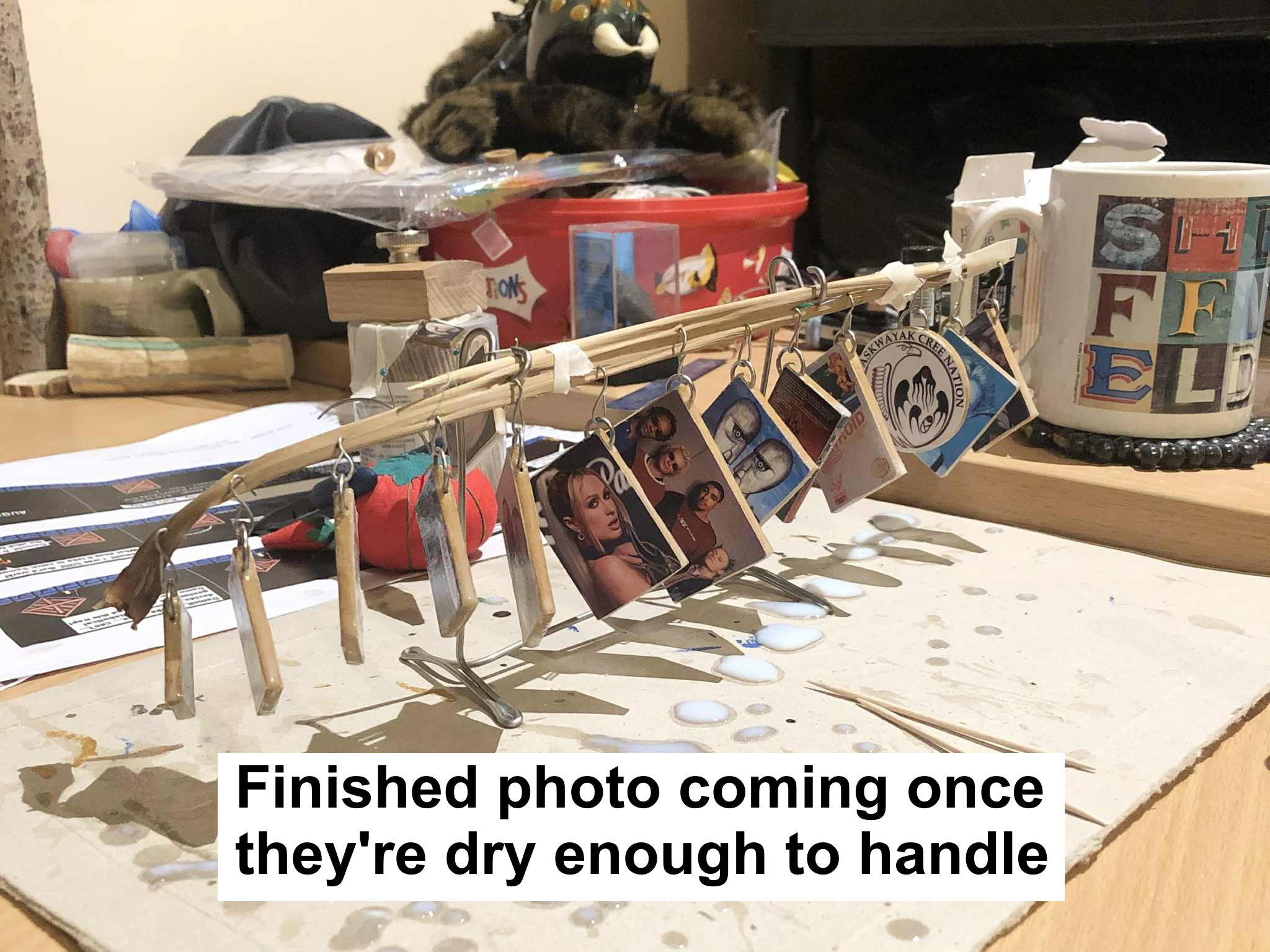 A photo of mostly finished photo ornaments, hanging to dry their varnish, with text saying finished photo coming once they're dry