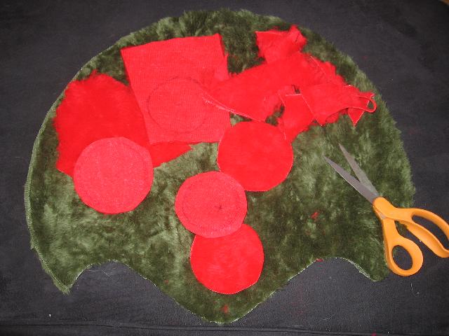 Most of the red circles cut out, and some scrap red fabric beside it, laying on top of the green sides.