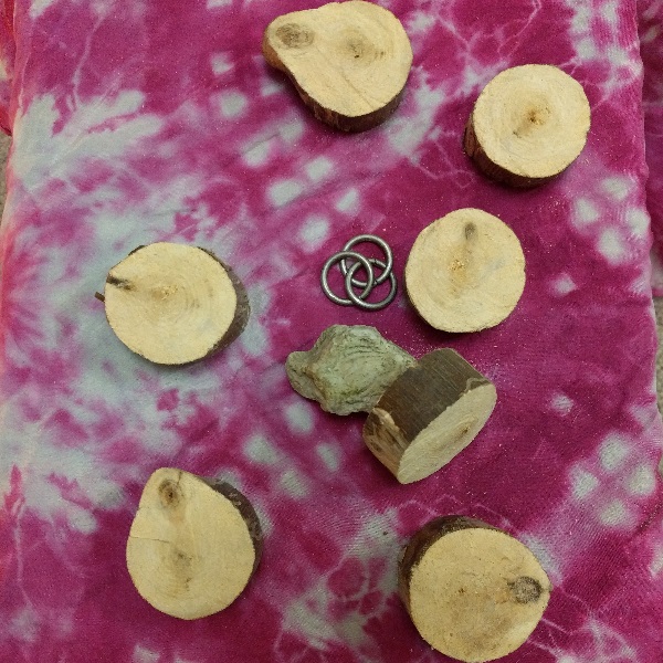 Seven wooden disks, a stone, and three interlocking metal rings on a silk cloth