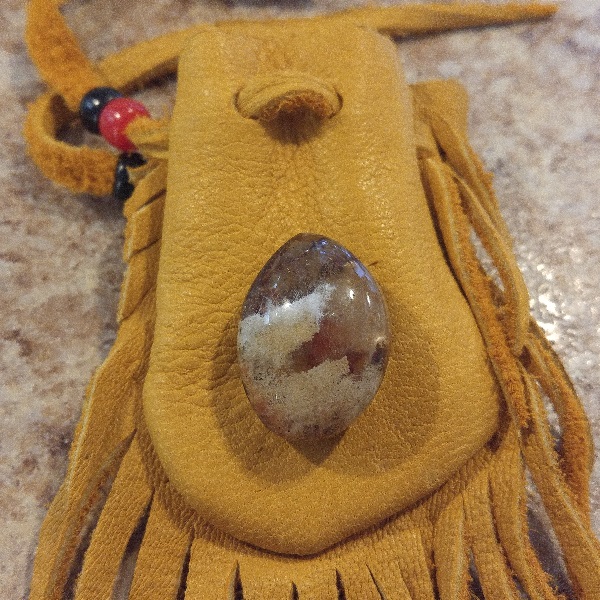 A leather pouch with a partially clouded clear stone on top