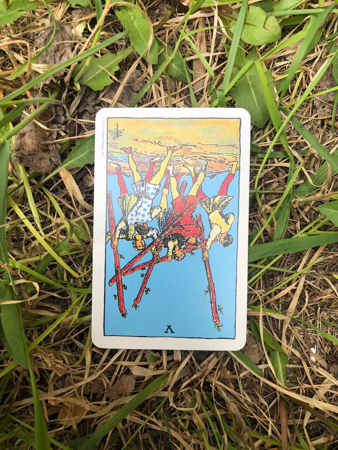 The Five of Wands, inverted, laying in the grass.