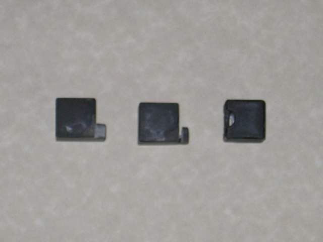 Three of the pieces, one showing an upright hook, and one showing a groove that you can see through.
