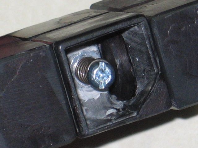 The middle piece with the cap removed, one corner still partially filled from the original cube, and a screw with a spring under it clearly visible inside.