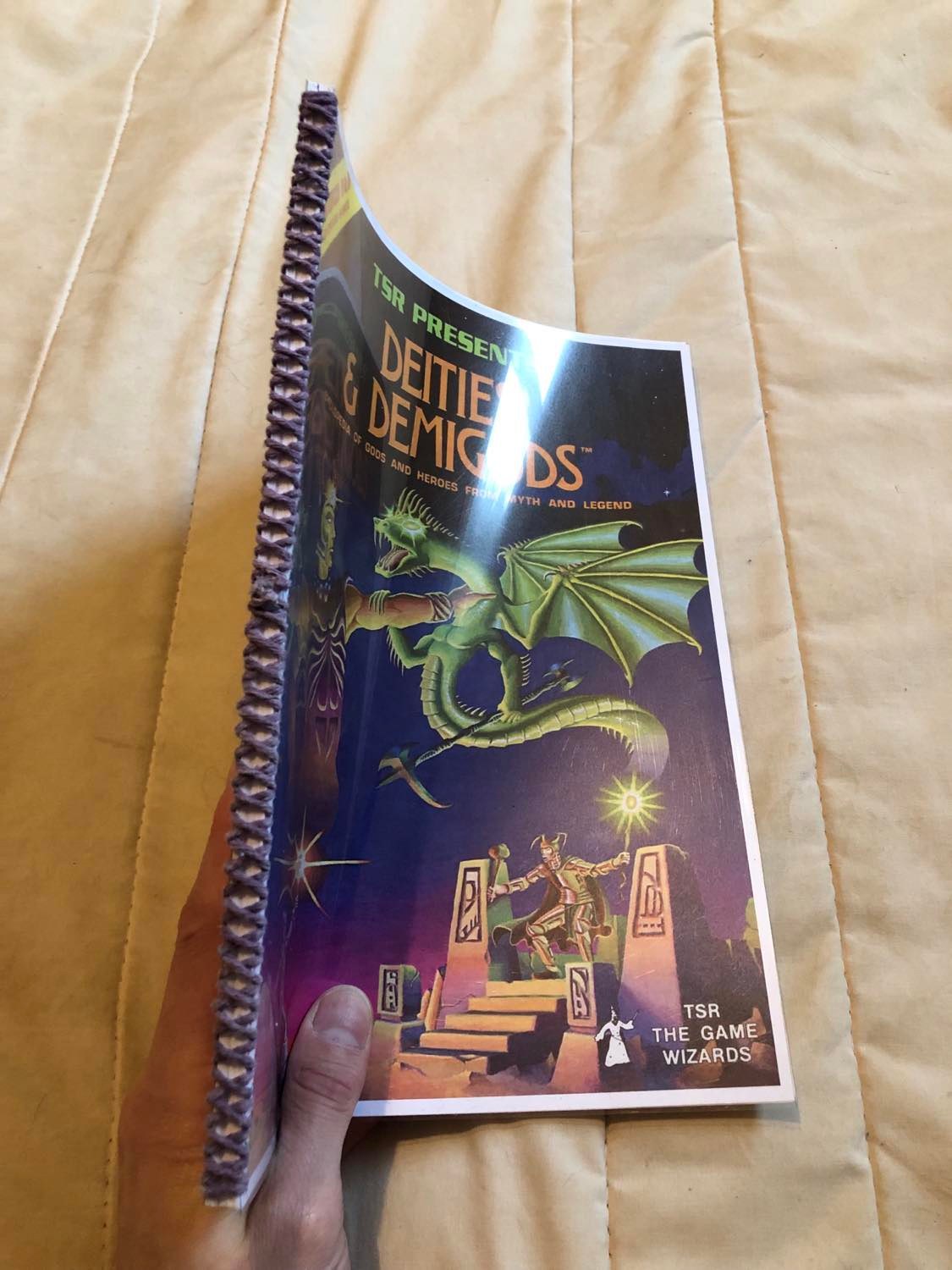 The book for Deities and Demigods, the first edition book, with a purple cover showing a golden God holding a giant Serpent, and a lower scene of a warrior approaching a giant stone throne with another figure on it, though I mainly just got this book to be able to talk to Deities from many different Religions.