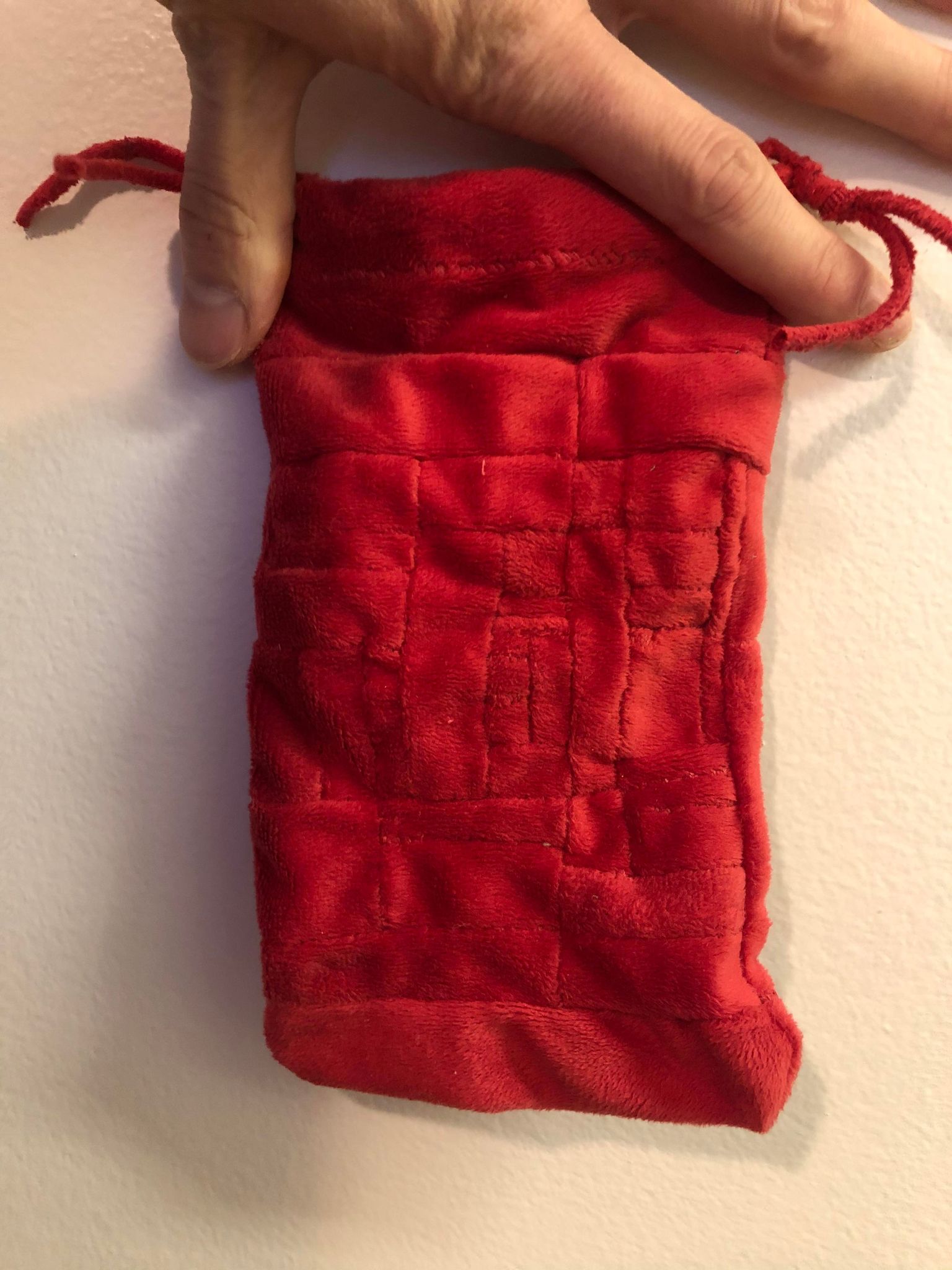 The other side of the bag, almost appearing as though wider bands are around the edges and it closes in towards smaller ones in the middle. The drawstring hangs to the right.