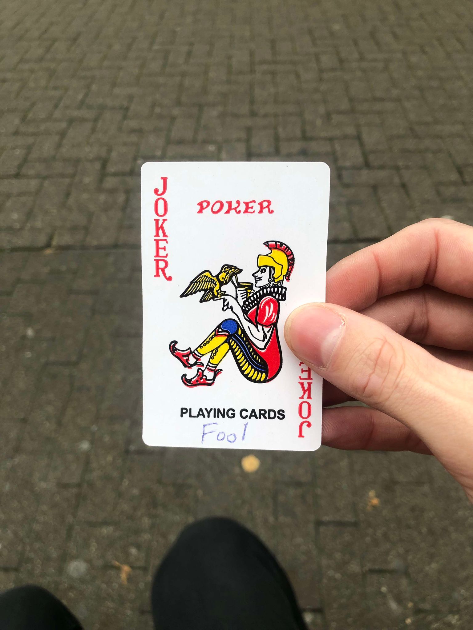 Sitting on a bench, a brick walkway in front of you, you hold the drawn card in front of you.