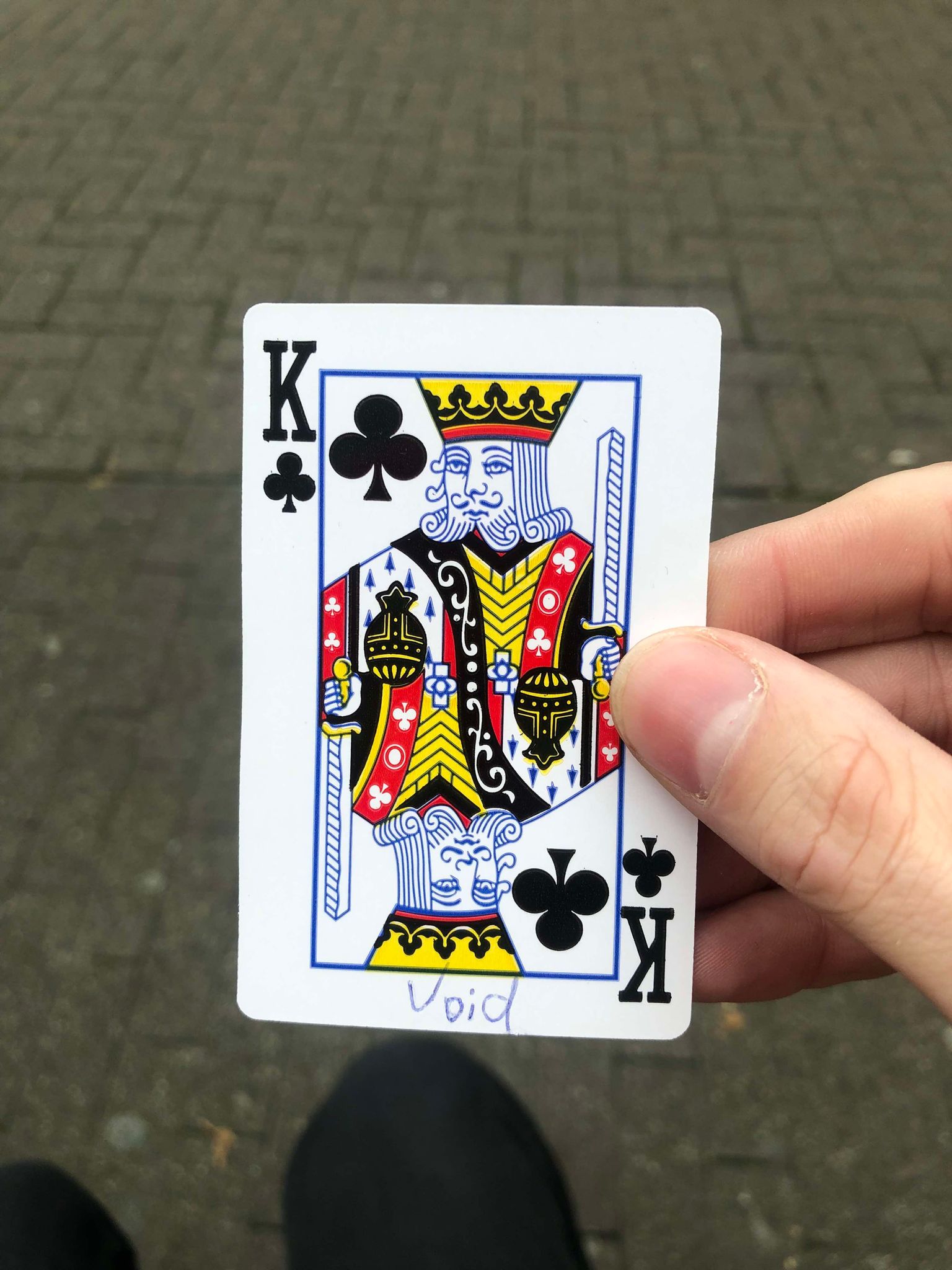 Sitting on a bench, a brick walkway in front of you, you hold the drawn card in front of you.
