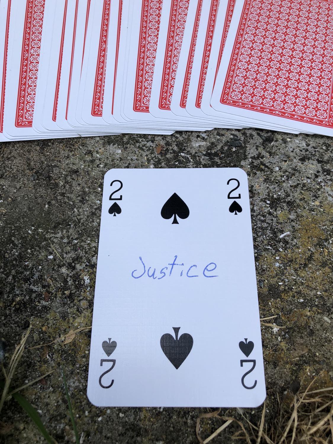 The two of spades with the word Justice written on it, laying on the bridge support.