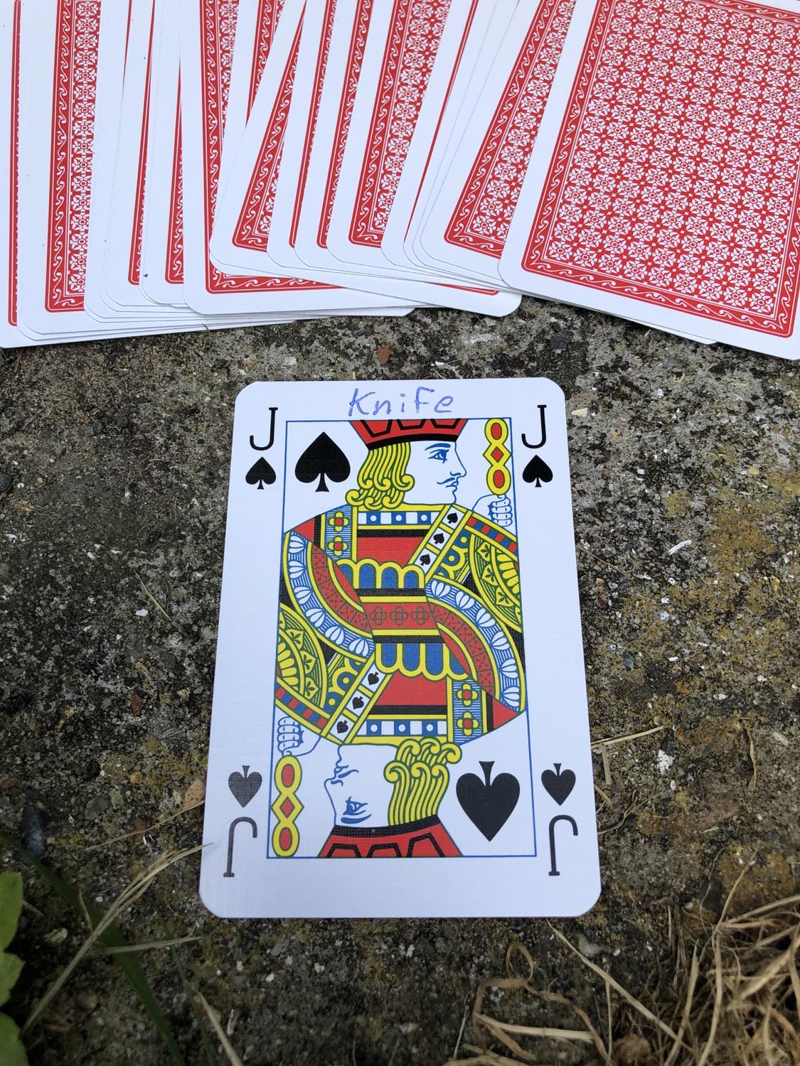 The jack of spades with the word Knife written on it, laying on the bridge support.