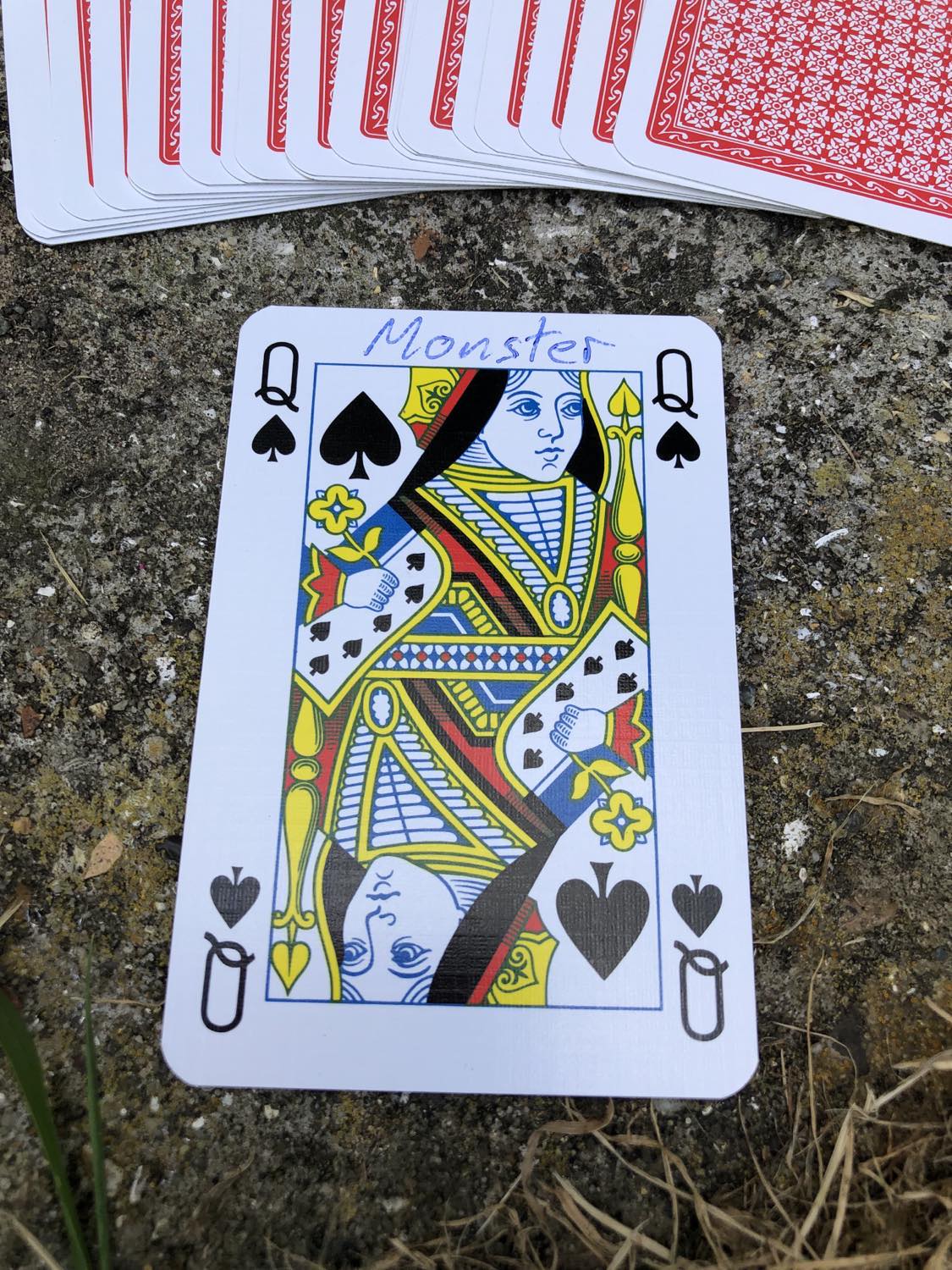 The queen of spades with the word Monster written on it, laying on the bridge support.