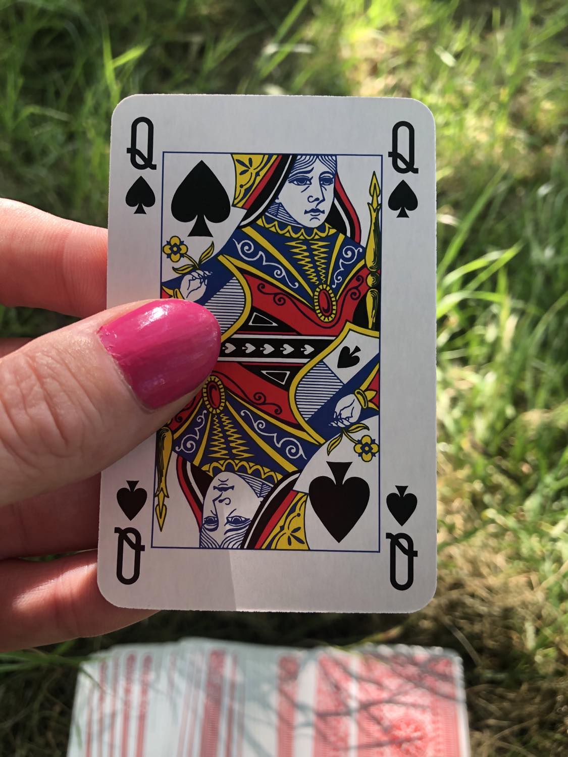 The queen of spades, held up from the drawn out cards.