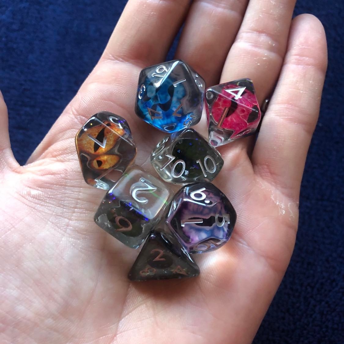 The Critical Kit dragon eye dice, resting in the palm, with several of the eyes visible through the clear dice.