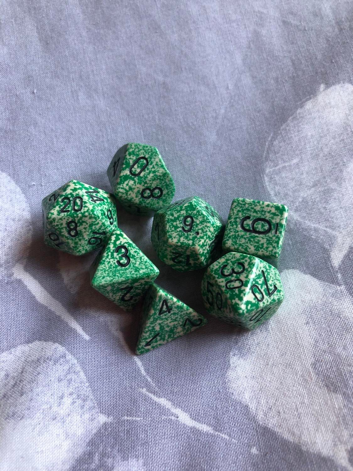 Chessex Speckled Loot, the very first dice set I ever owned, sitting on a grey and white leaf-patterned fabric.