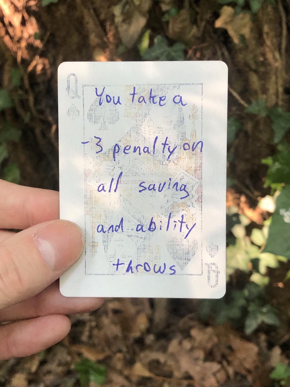 The queen of spades, held above the detritus on the ground. You take a -3 penalty to all saving and ability throws.