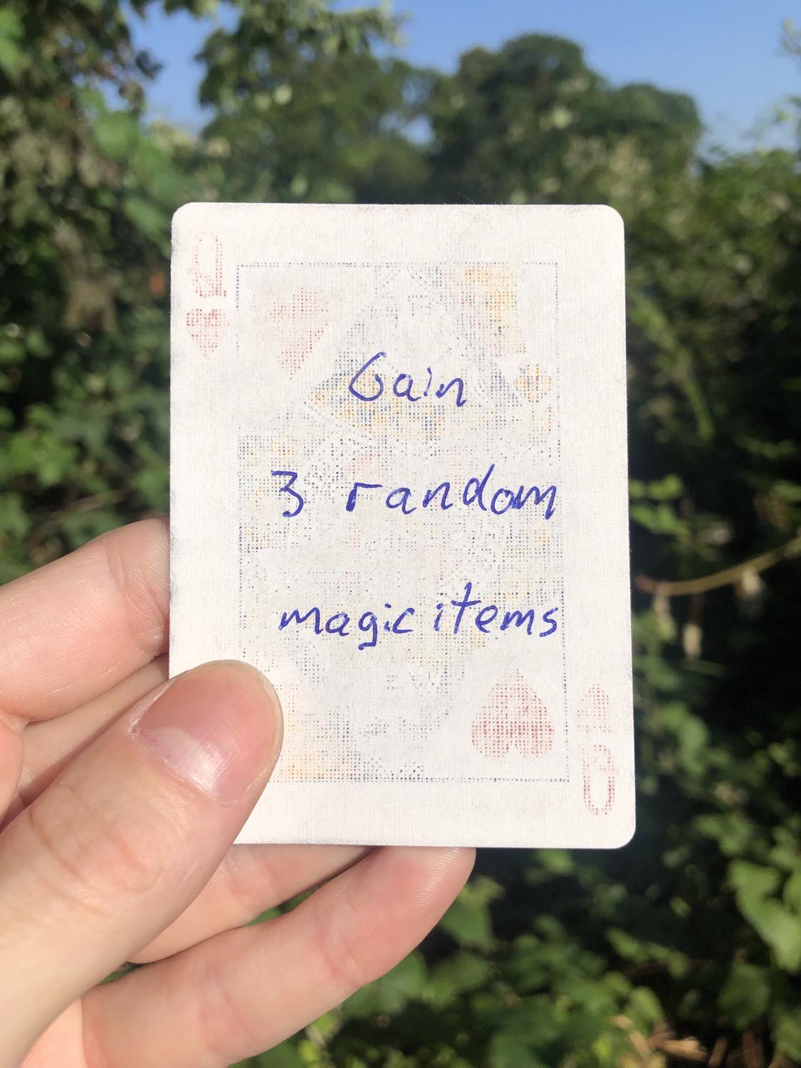 The queen of hearts, held with the trees and foliage behind. Gain 3 random magic items.