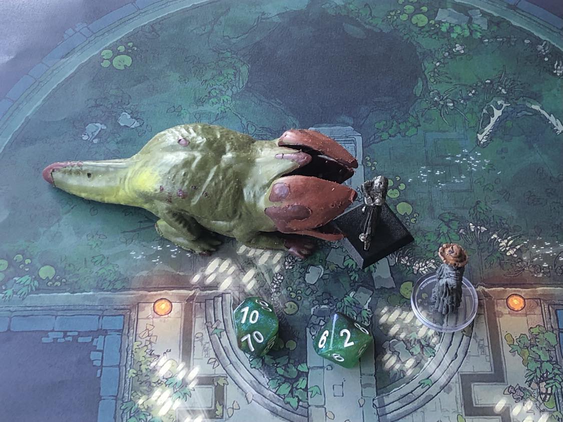 The battle map from above, with the monk fully attacking the creature, and the sorcerer rolling a pair of d10 dice to determine the wild magic surge.