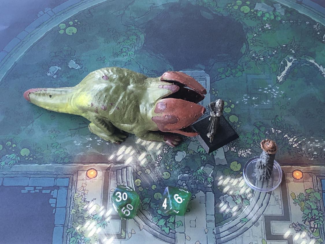 The battle map from above, with the monk fully attacking the creature, and the sorcerer rolling a pair of d10 dice to determine the wild magic surge.