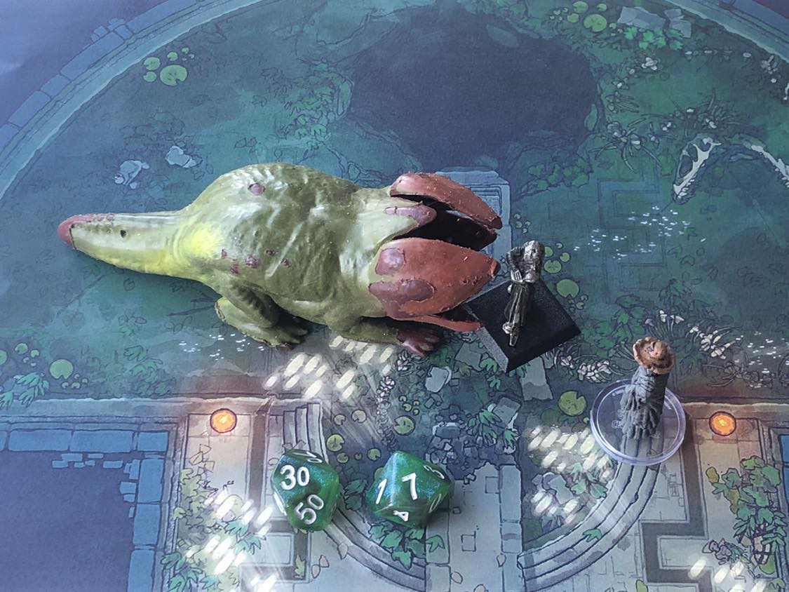The battle map from above, with the monk fully attacking the creature, and the sorcerer rolling a pair of d10 dice to determine the wild magic surge.