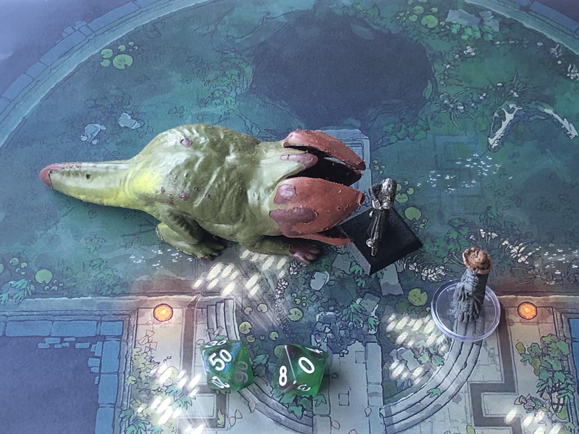 The battle map from above, with the monk fully attacking the creature, and the sorcerer rolling a pair of d10 dice to determine the wild magic surge.
