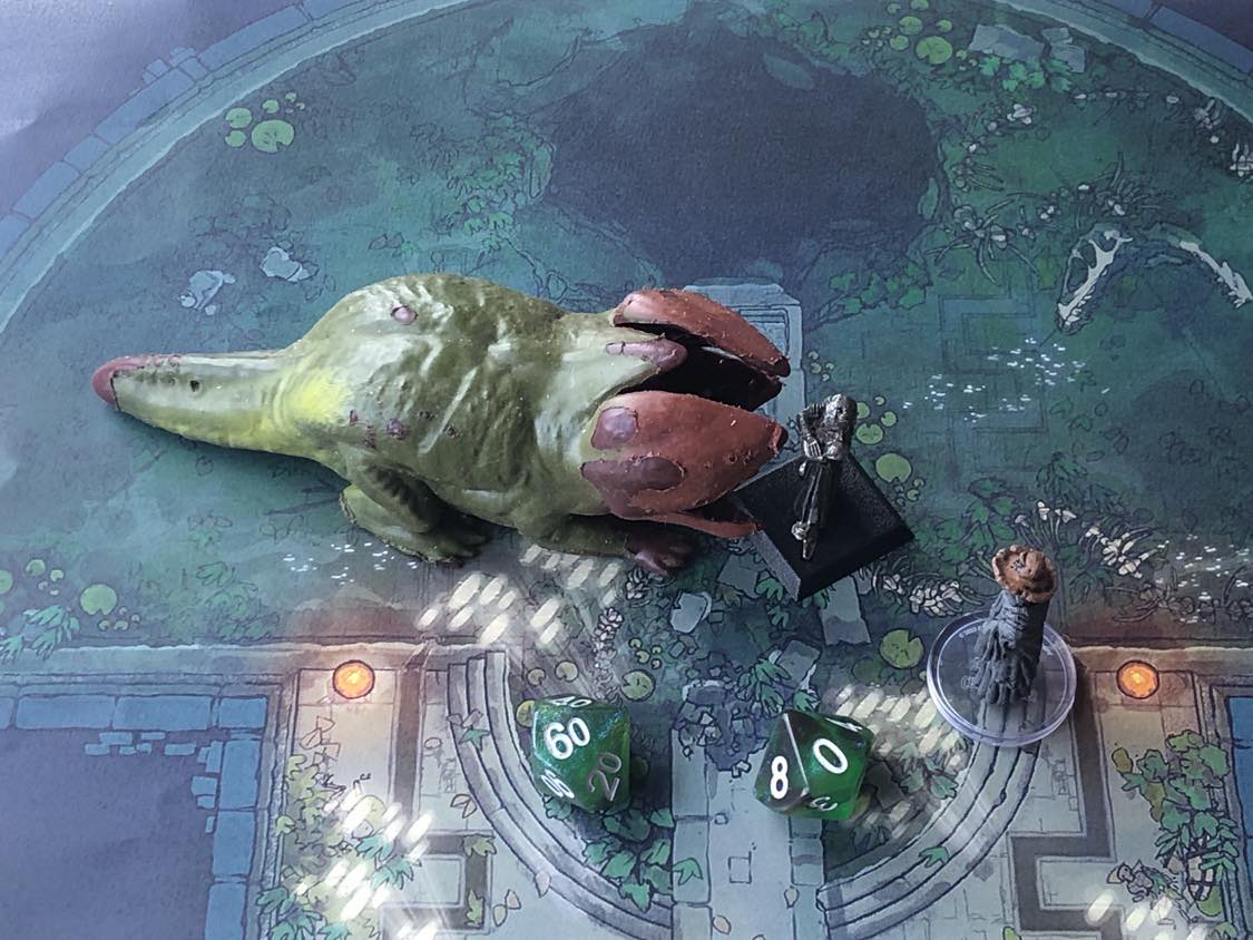 The battle map from above, with the monk fully attacking the creature, and the sorcerer rolling a pair of d10 dice to determine the wild magic surge.