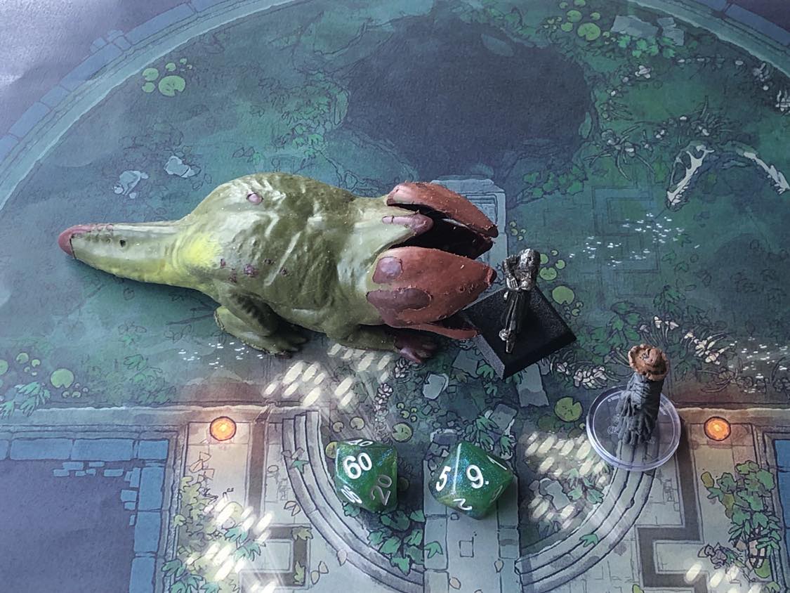 The battle map from above, with the monk fully attacking the creature, and the sorcerer rolling a pair of d10 dice to determine the wild magic surge.